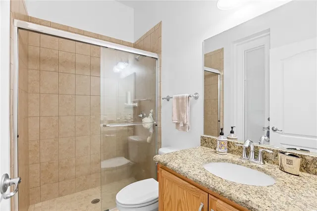 a bathroom with a granite countertop sink toilet mirror and shower