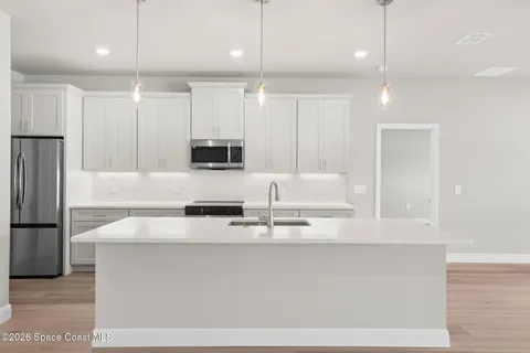 a kitchen with stainless steel appliances kitchen island a sink dishwasher a refrigerator and a wooden cabinets