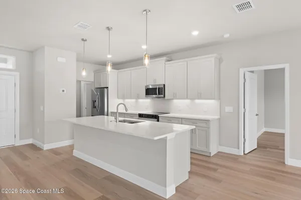 a kitchen with stainless steel appliances kitchen island a sink dishwasher a refrigerator and a wooden cabinets