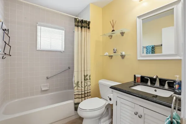 a bathroom with a granite countertop sink a toilet a mirror and shower