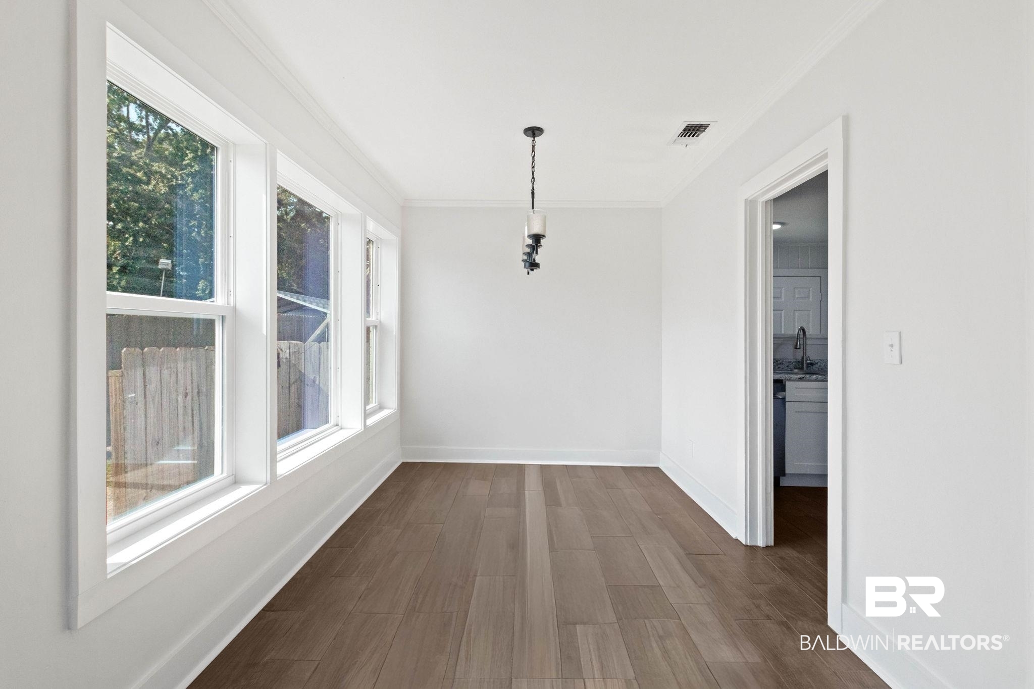 311 Cloverdale Road Atmore, AL 36502 - Photo 3 of 63 Dining area featuring wood-finish flooring, a series of three windows, crisp white walls, white trim, and a ceiling-mounted light fixture