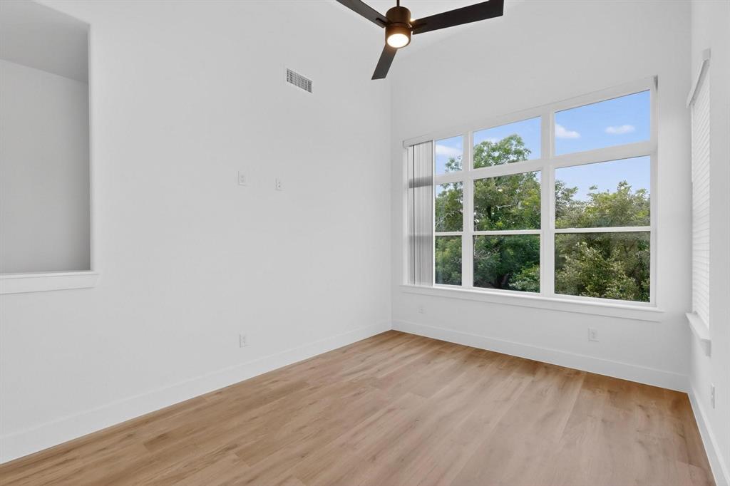 2226 Shea Road, Unit 103 Dallas, TX 75235 - Photo 14 of 35 Room featuring a large multi-pane window, wood-finish flooring, a modern ceiling fan, and white walls