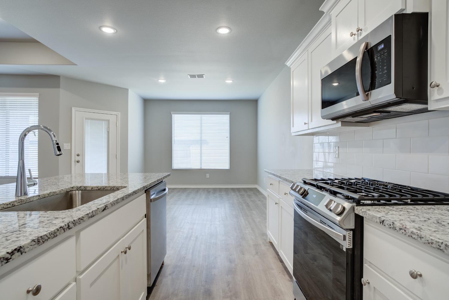 7602 60th Street Lubbock, TX 79407 - Photo 17 of 33 a kitchen with stainless steel appliances granite countertop a stove a sink and a microwave
