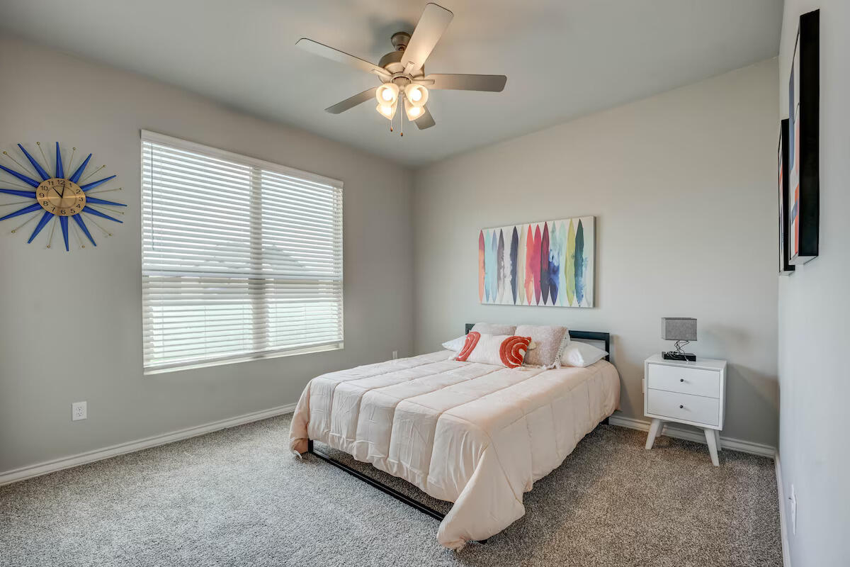 7602 60th Street Lubbock, TX 79407 - Photo 23 of 33 a bedroom with a bed and a chandelier