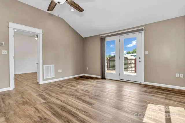 a view of an empty room with wooden floor and a window