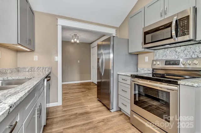 a kitchen with stainless steel appliances granite countertop a stove microwave and sink