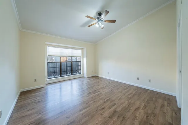 an empty room with wooden floor and ceiling fan