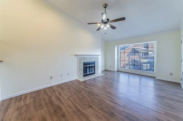 a view of an empty room with wooden floor fireplace and a window