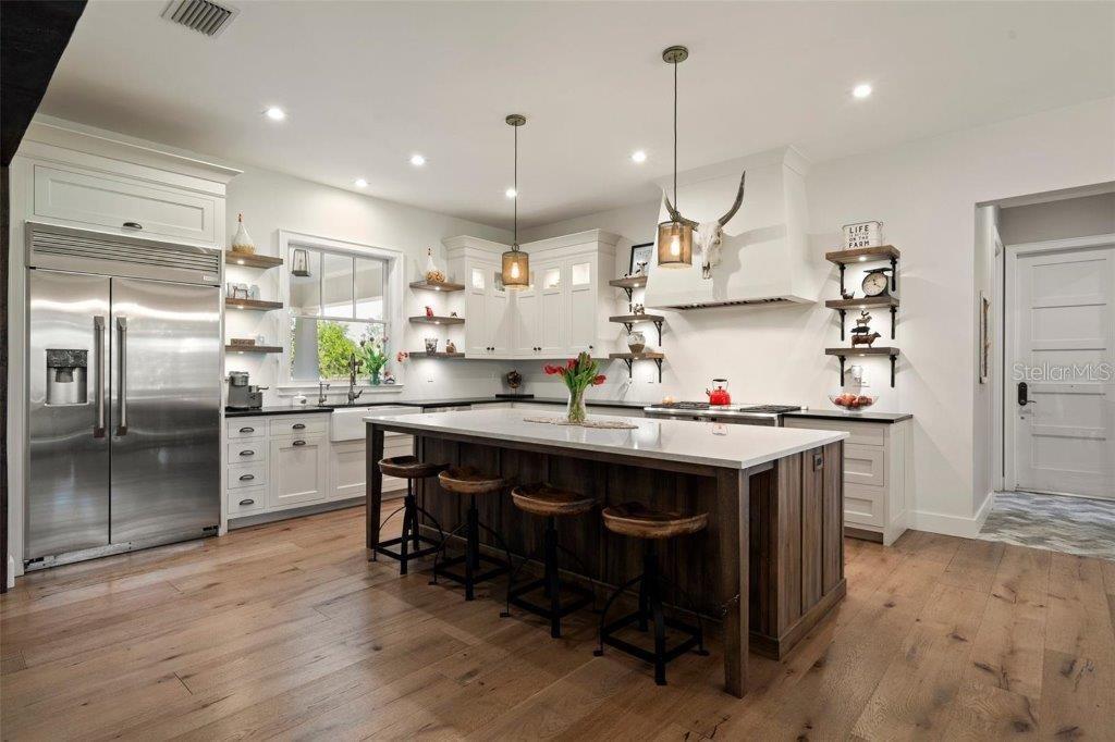 12615 River Road Myakka City, FL 34251 - Photo 15 of 88 a kitchen with kitchen island a wooden floor and a refrigerator