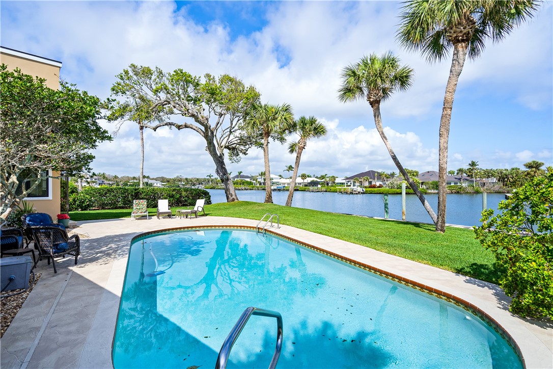 635 Live Oak Road Vero Beach, FL 32963 - Photo 28 of 35 a view of a swimming pool with a lawn chairs under an umbrella