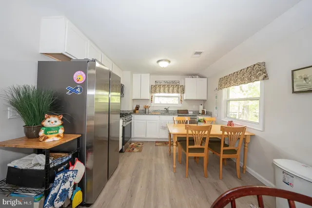 a kitchen with stainless steel appliances granite countertop a stove oven a sink dishwasher and white cabinets with wooden floor