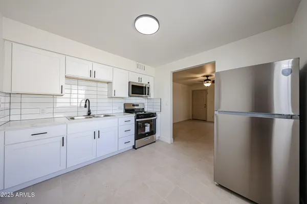 a kitchen with white cabinets a sink and a stove with wooden floor