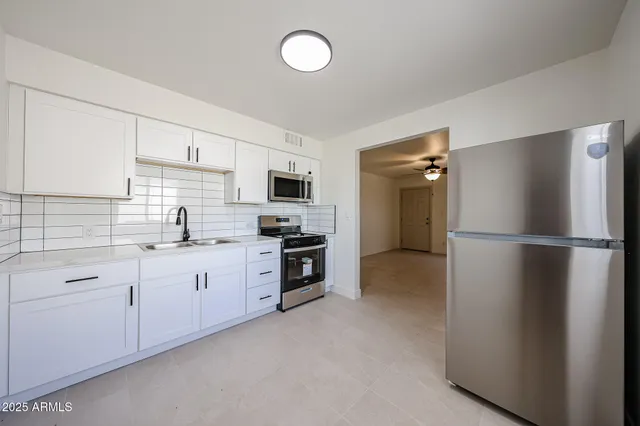 a kitchen with white cabinets a sink and a stove with wooden floor