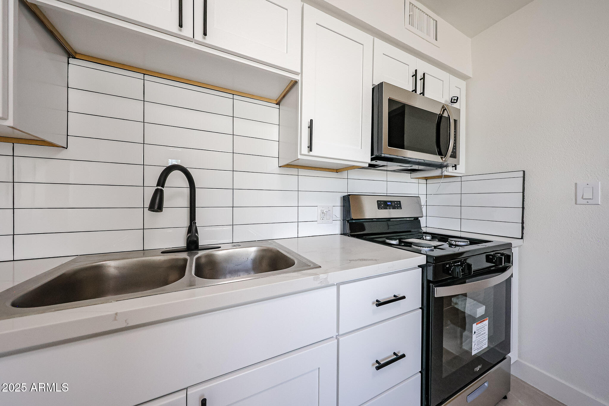 10202 North 15th Avenue, Unit 2 Phoenix, AZ 85021 - Photo 19 of 34 a kitchen with white cabinets a sink and a stove with wooden floor
