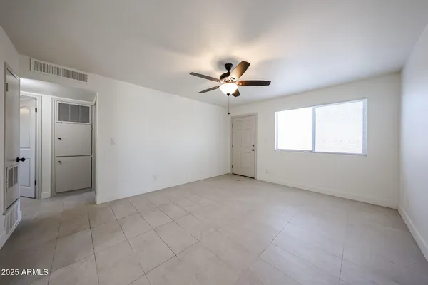 an empty room with windows and chandelier fan