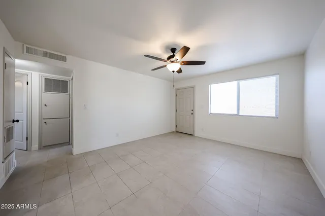 an empty room with windows and chandelier fan