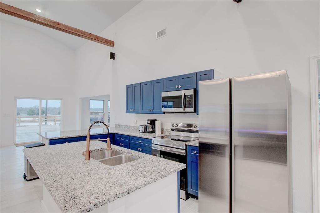 550 County Road 297 Gainesville, TX 76240 - Photo 7 of 24 a kitchen with kitchen island a sink refrigerator and microwave