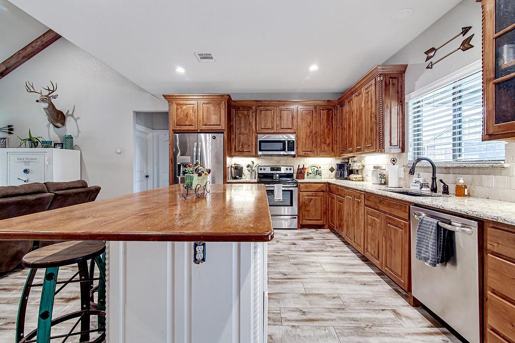 3817 Cross Timber Road Burleson, TX 76028 - Photo 14 of 36 a kitchen with kitchen island a stove a sink a refrigerator and a refrigerator
