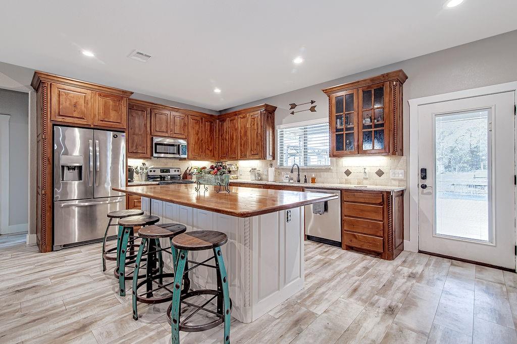 3817 Cross Timber Road Burleson, TX 76028 - Photo 15 of 36 a kitchen with a refrigerator a stove top oven a sink dishwasher and white cabinets with wooden floor