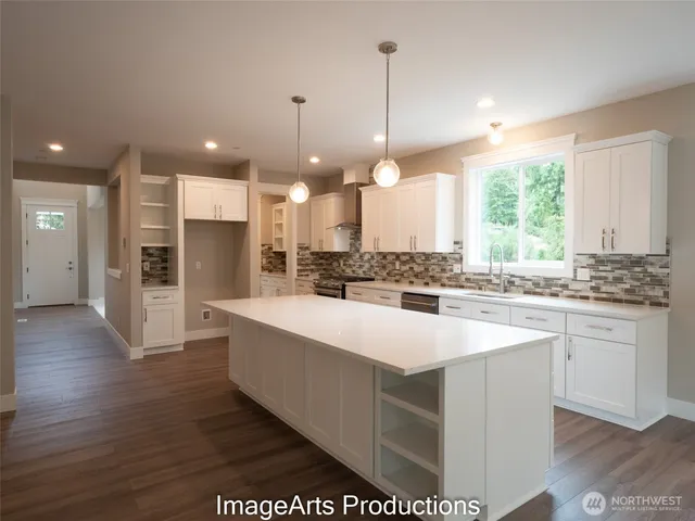 a large kitchen with kitchen island white cabinets and stainless steel appliances