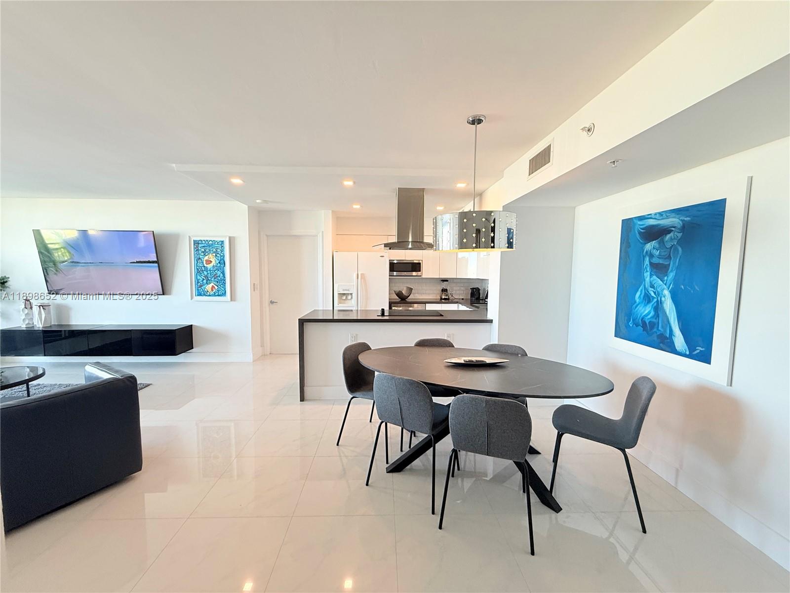 90 Alton Road, Unit 909 Miami Beach, FL 33139 - Photo 24 of 37 a kitchen with stainless steel appliances kitchen island granite countertop a dining table chairs and a refrigerator