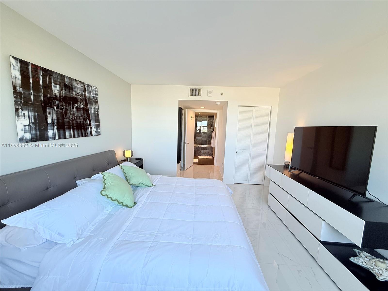 90 Alton Road, Unit 909 Miami Beach, FL 33139 - Photo 29 of 37 a bedroom with a bed and a flat screen tv