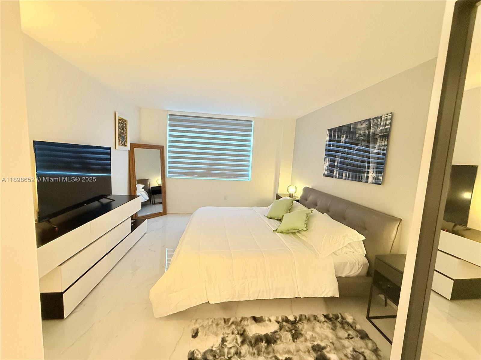 90 Alton Road, Unit 909 Miami Beach, FL 33139 - Photo 30 of 37 a bedroom with a bed and wooden floor