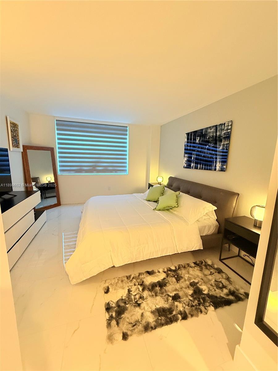 90 Alton Road, Unit 909 Miami Beach, FL 33139 - Photo 31 of 37 a bedroom with a bed and wooden floor