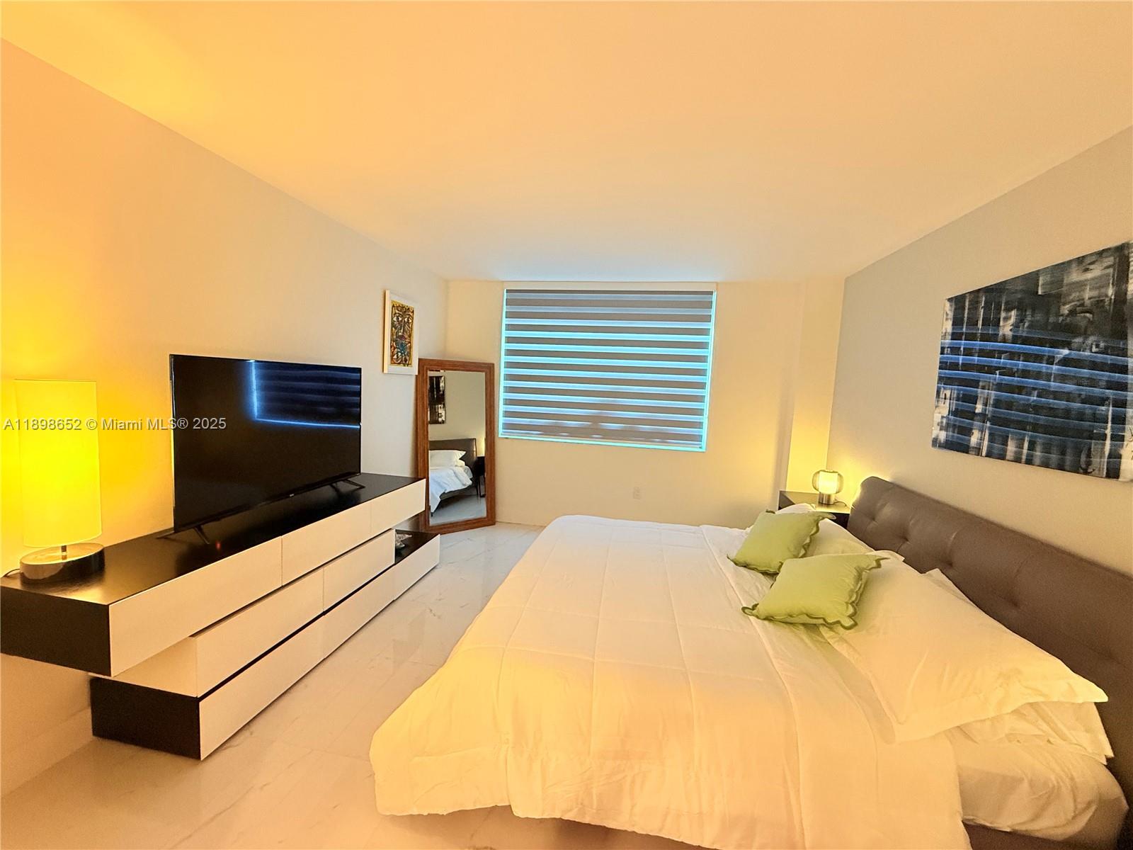 90 Alton Road, Unit 909 Miami Beach, FL 33139 - Photo 32 of 37 a bedroom with a bed and flat screen tv