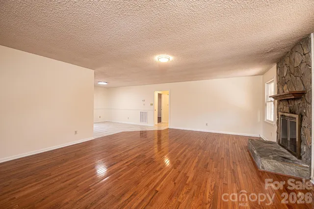 a view of empty room with wooden floor and fireplace