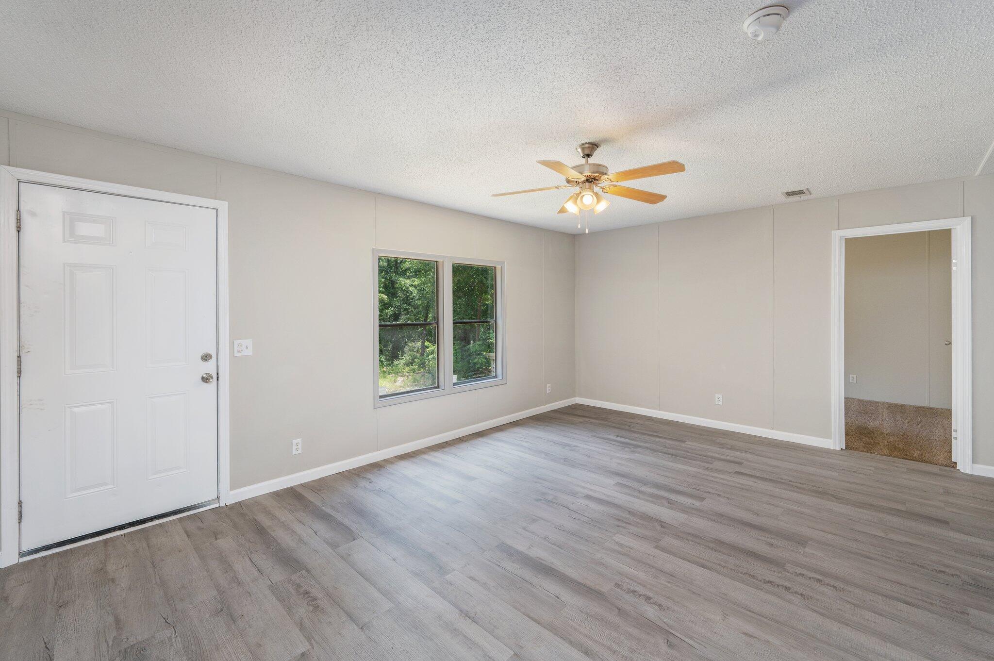 4231 Painter Branch Road Crestview, FL 32539 - Photo 18 of 39 an empty room with wooden floor and a ceiling fan