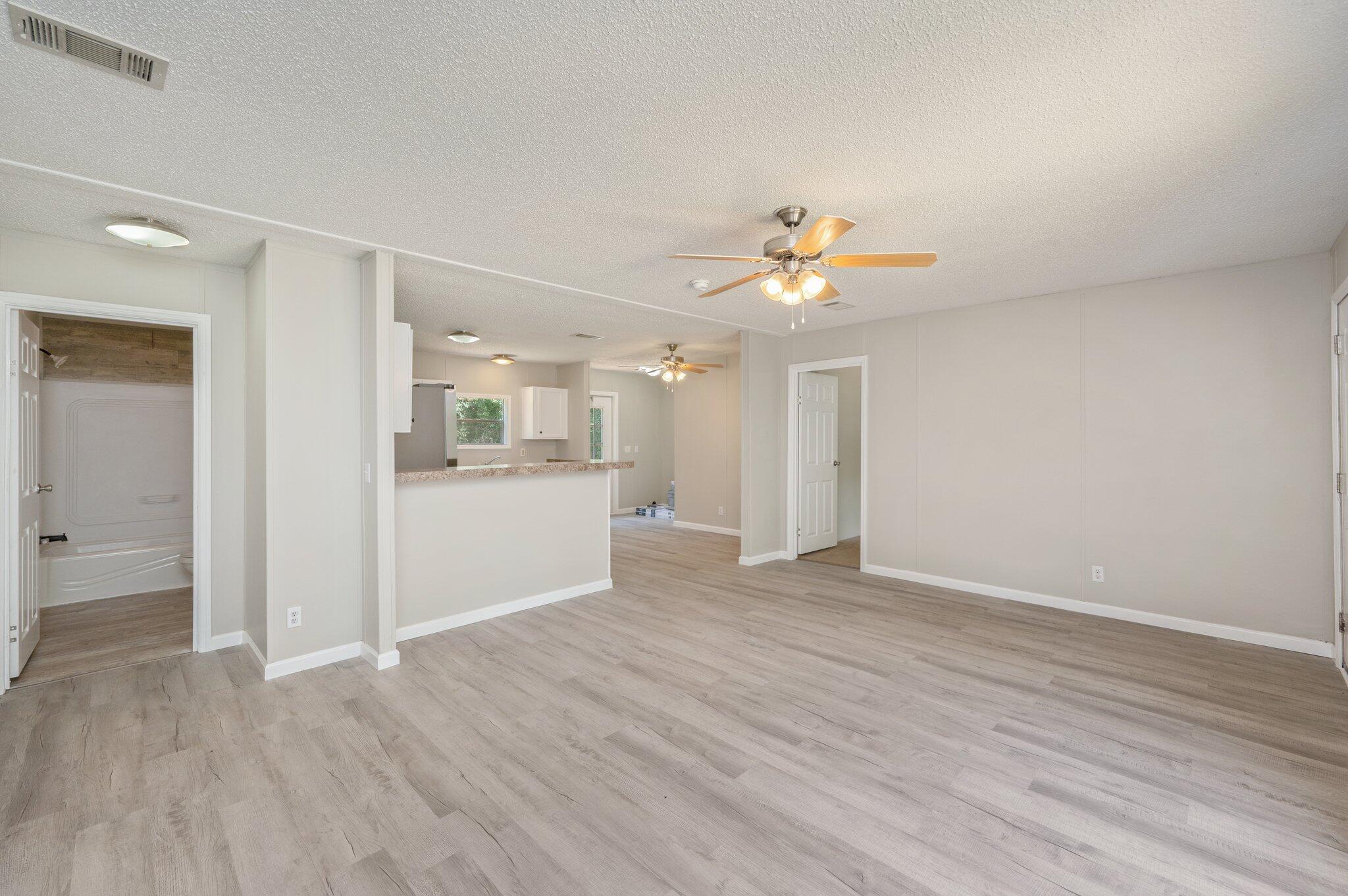 4231 Painter Branch Road Crestview, FL 32539 - Photo 20 of 39 a view of an empty room with wooden floor and a kitchen