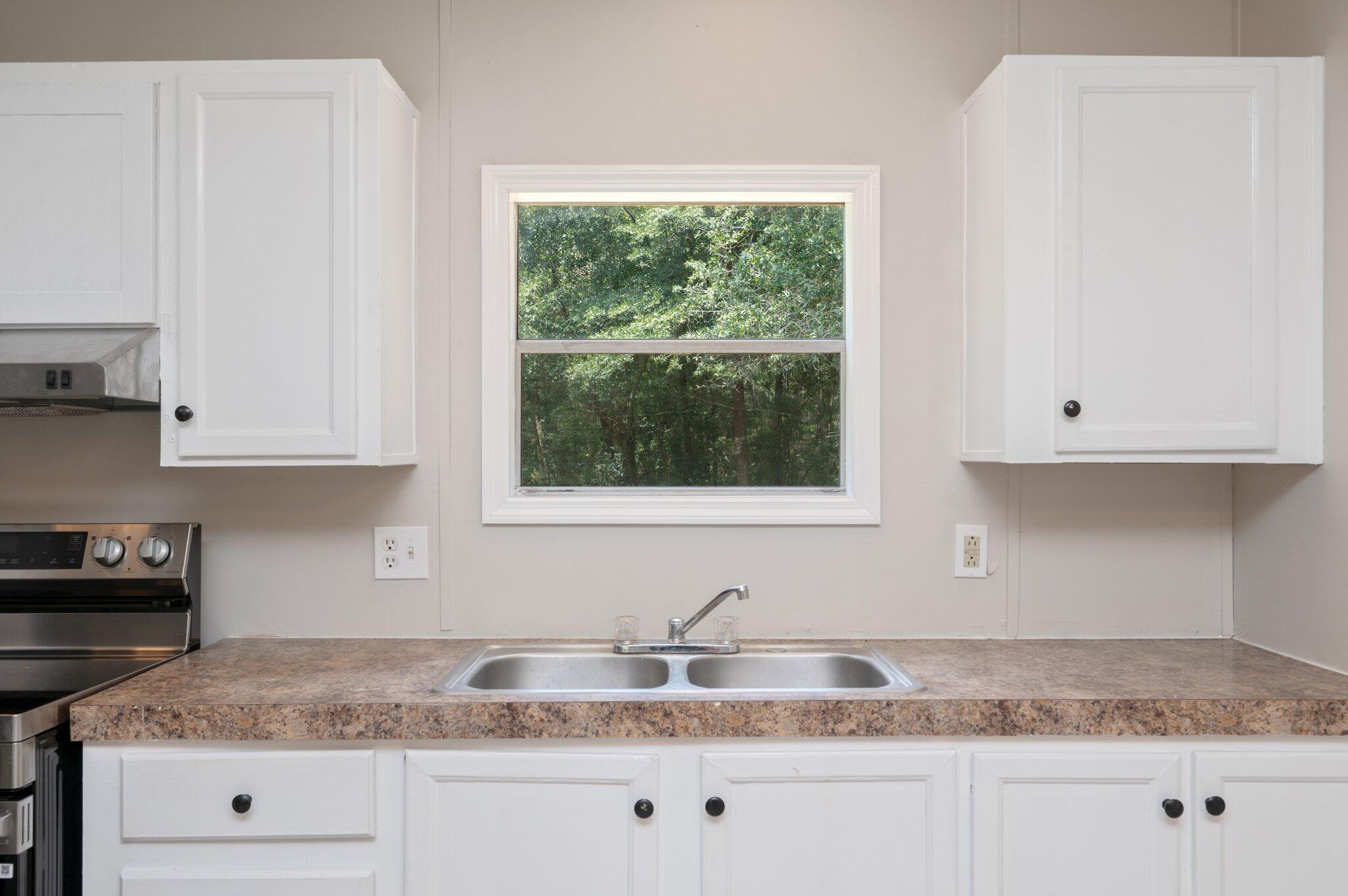 4231 Painter Branch Road Crestview, FL 32539 - Photo 24 of 39 a kitchen with granite countertop white cabinets and a window