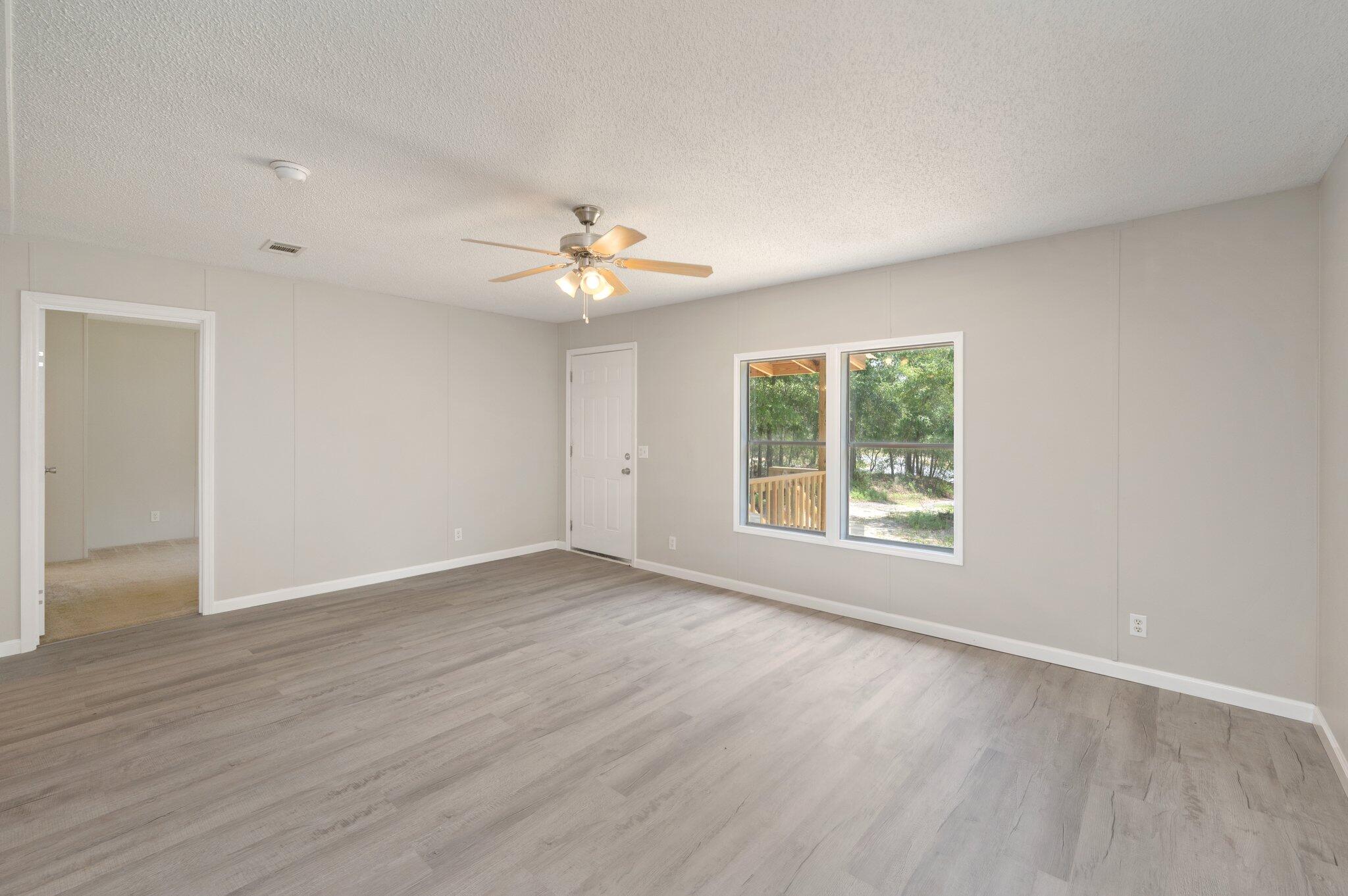 4231 Painter Branch Road Crestview, FL 32539 - Photo 5 of 39 an empty room with wooden floor and windows