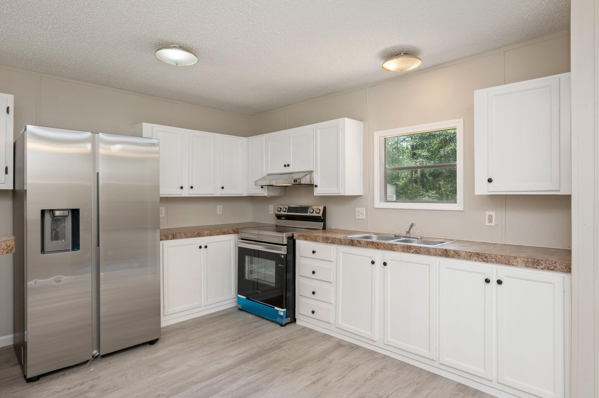 4231 Painter Branch Road Crestview, FL 32539 - Photo 6 of 39 a kitchen with granite countertop white cabinets white appliances a sink and a window