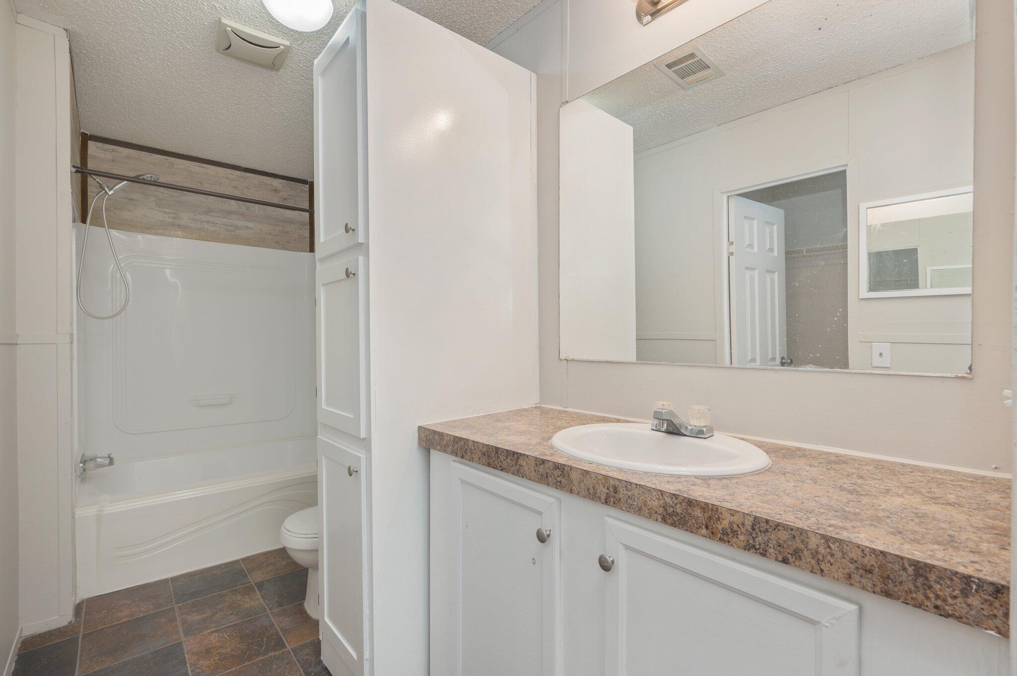 4231 Painter Branch Road Crestview, FL 32539 - Photo 9 of 39 a bathroom with a granite countertop sink mirror and a bathtub