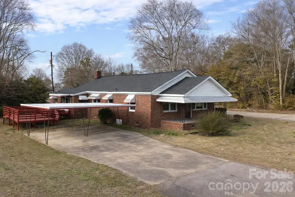 a view of a house with a cars park side of a road