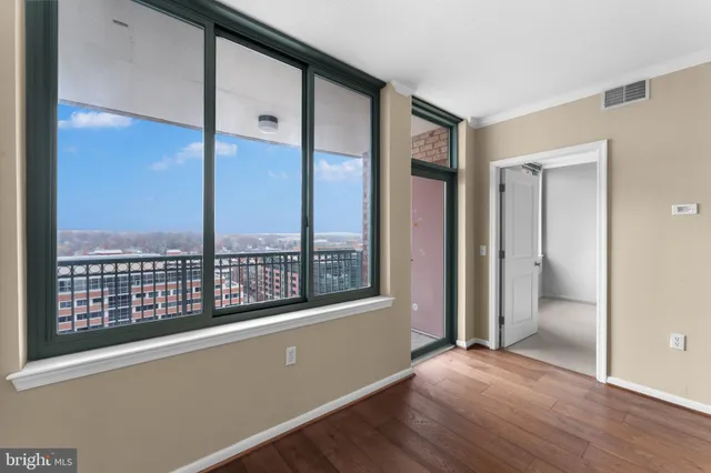 an empty room with wooden floor and windows