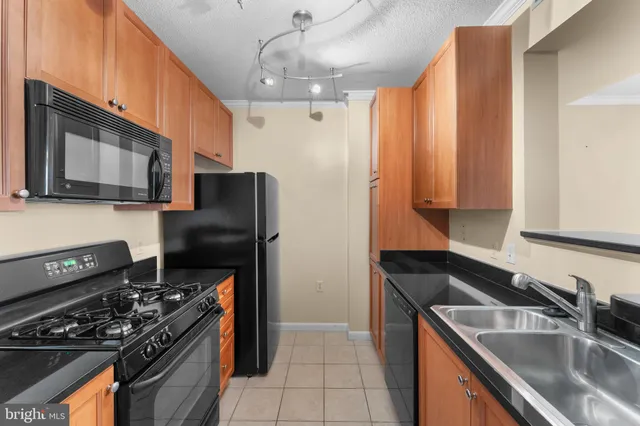a kitchen that has a sink wooden cabinets and stainless steel appliances