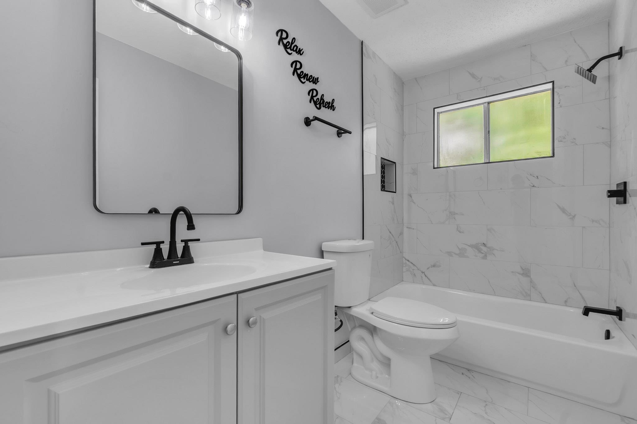 3314 Bright Ridge Cove Memphis, TN 38115 - Photo 13 of 16 Bathroom featuring a white vanity with integrated sink, black fixtures, and a framed mirror