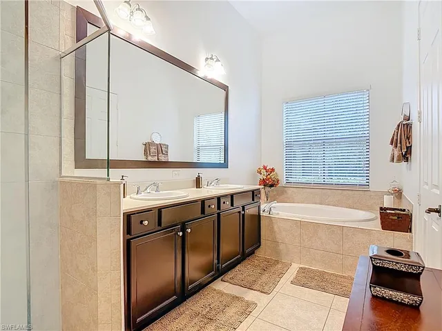a spacious bathroom with a tub sink and mirror