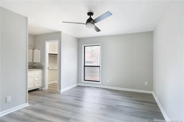 a view of empty room with wooden floor and fan