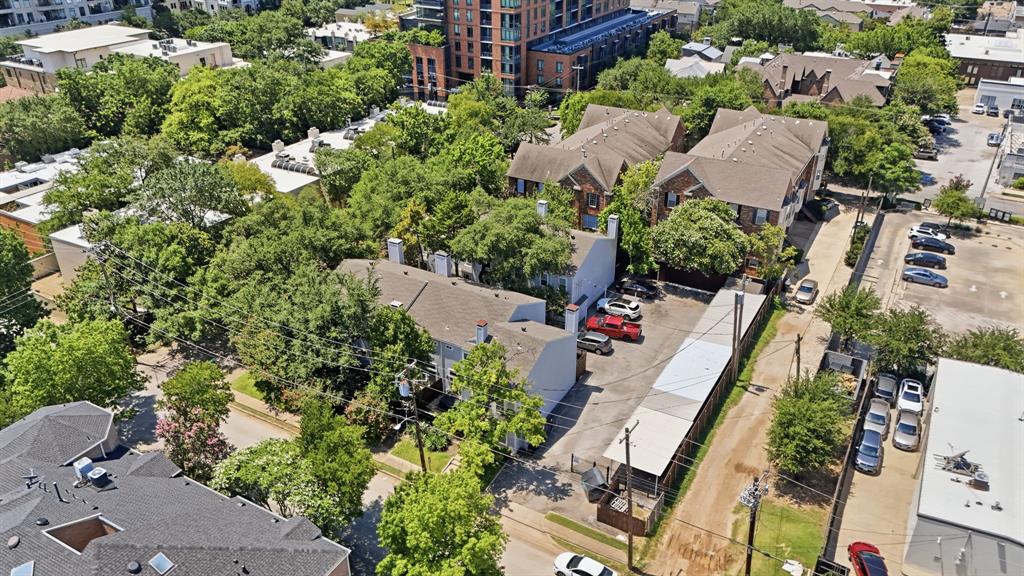 2815 Welborn Street, Unit 101 Dallas, TX 75219 - Photo 28 of 29 Multiple residential structures with brown shingle roofing and brick facades surrounded by mature trees