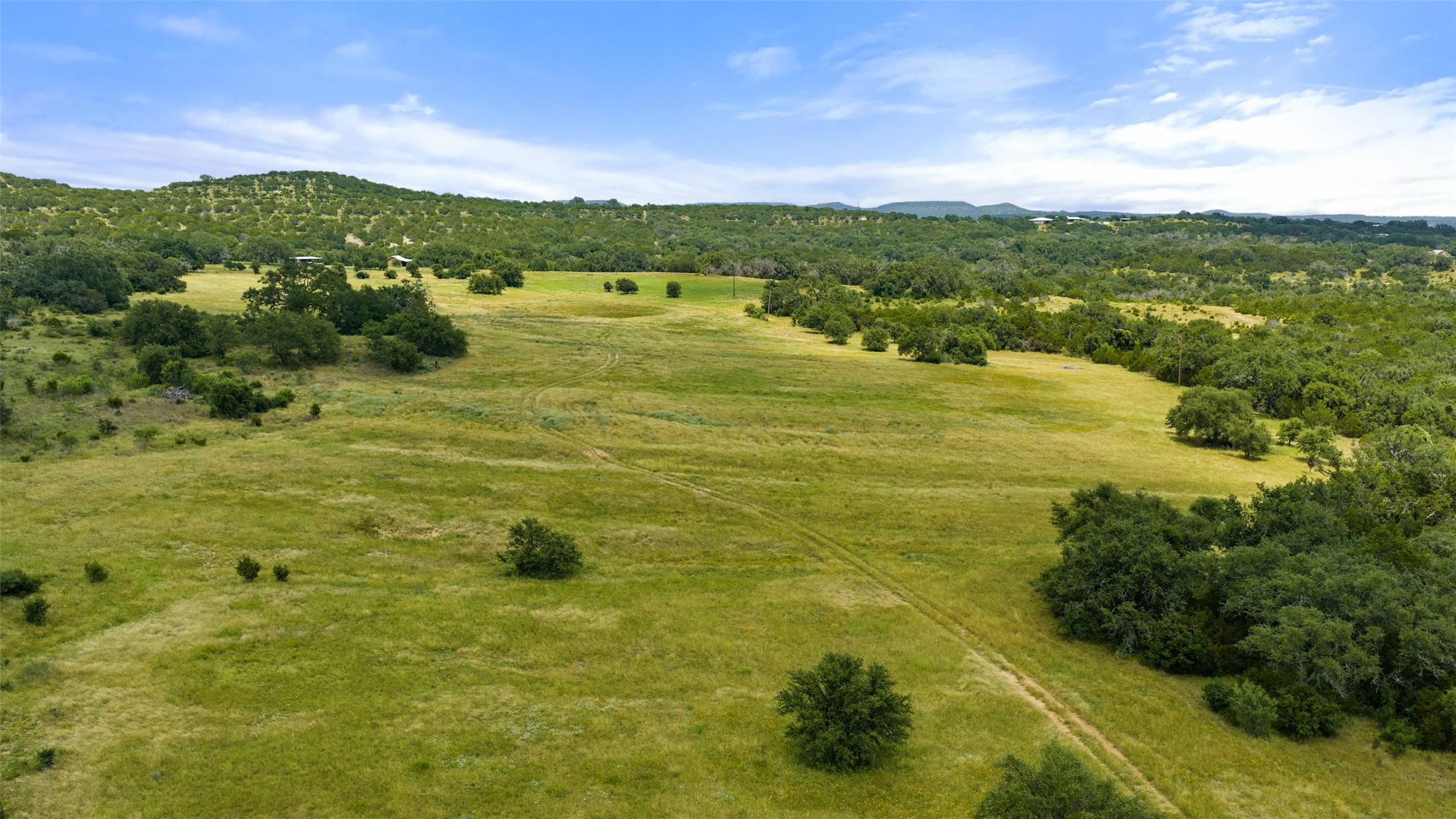 8400 Ranch Road 1431 Marble Falls, TX 78654 - Photo 22 of 30 Vast green meadows framed by verdant hills and scattered mature trees create an idyllic natural setting.