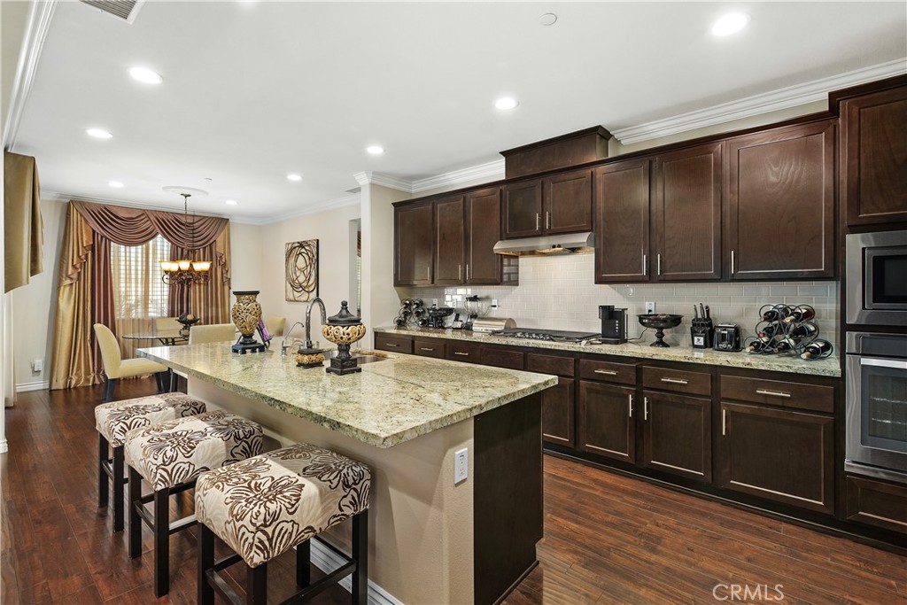 24128 Deputy Way Menifee, CA 92584 - Photo 9 of 34 a kitchen with granite countertop sink stove dining table and chairs