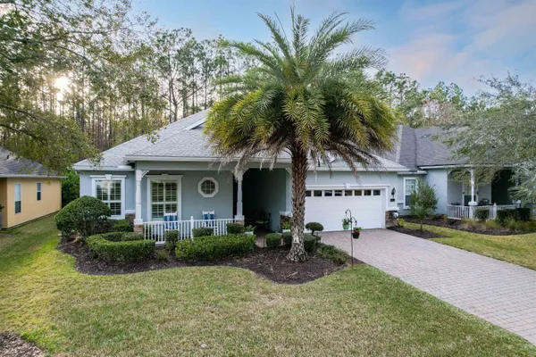 a front view of a house with garden and trees
