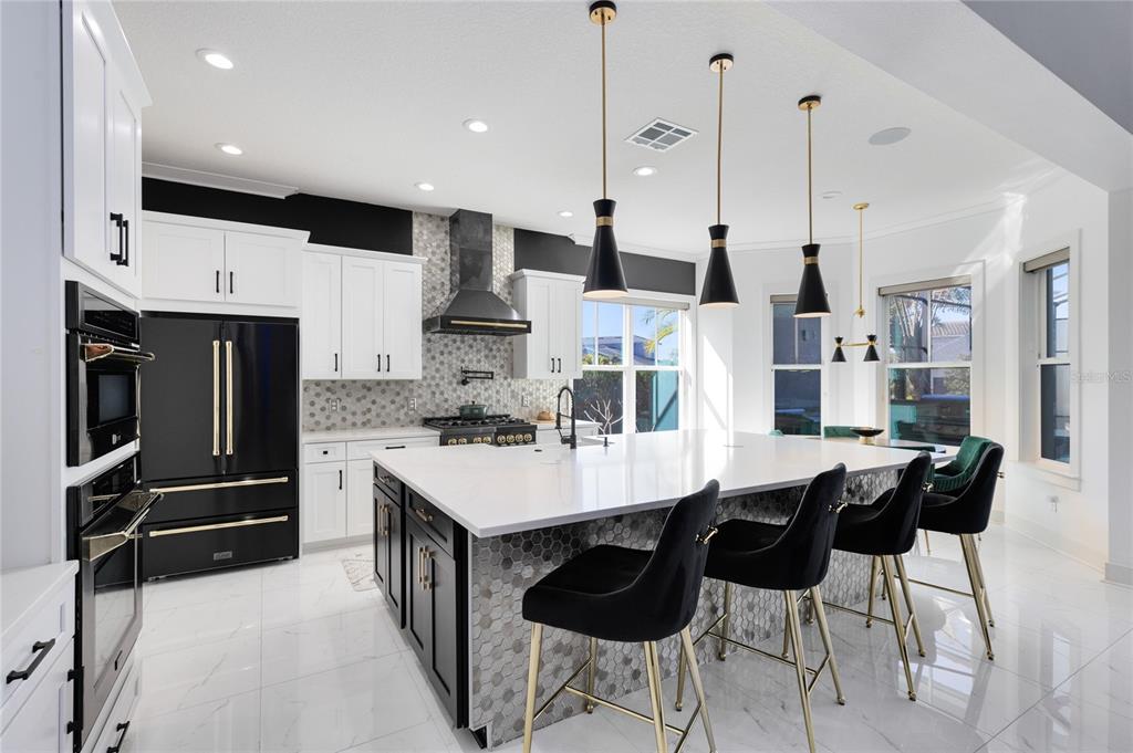 12664 Banting Terrace Orlando, FL 32827 - Photo 18 of 79 a kitchen with stainless steel appliances kitchen island granite countertop a table chairs and a refrigerator