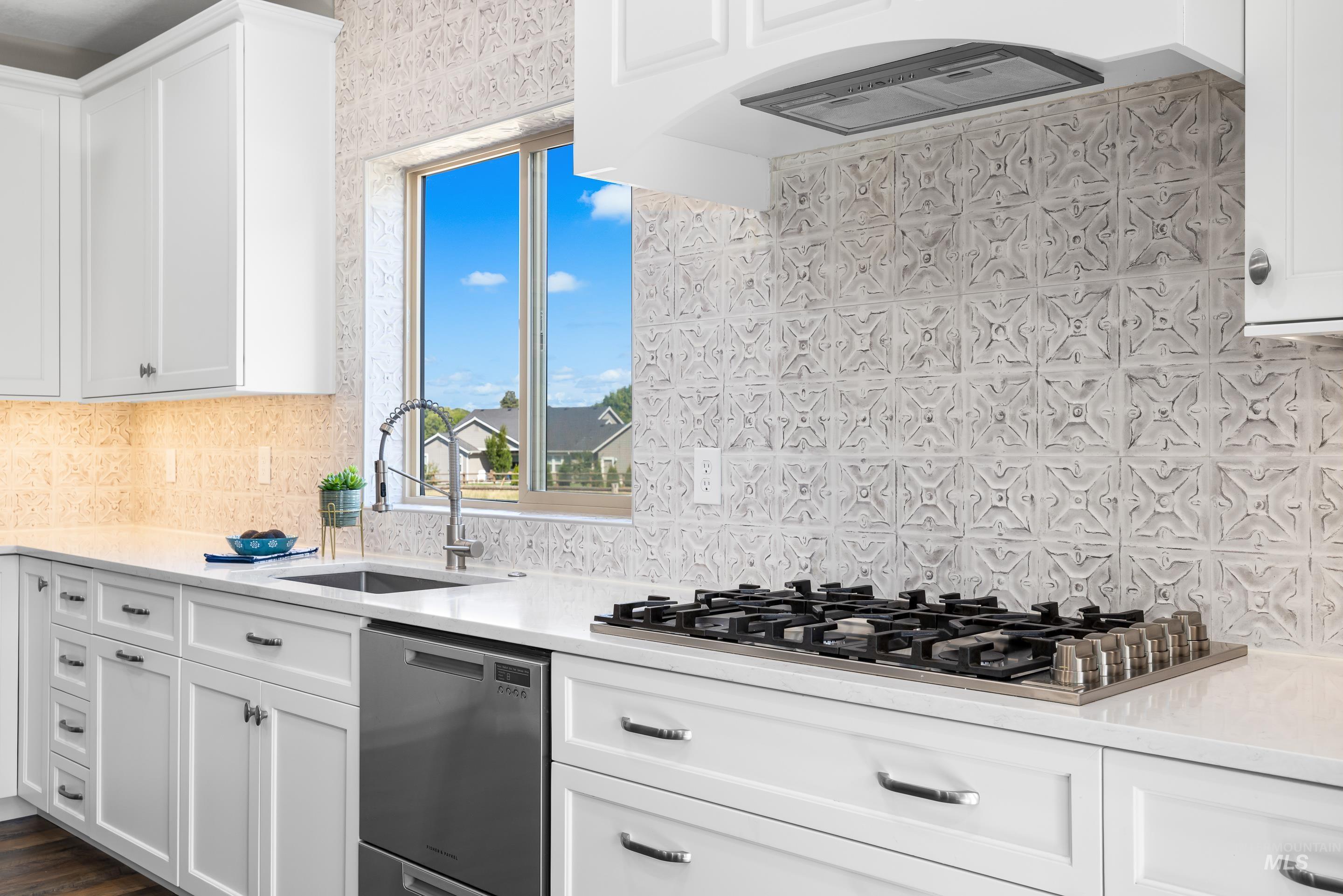 14119 Silver Ridge Road Caldwell, ID 83607 - Photo 18 of 50 Kitchen featuring white cabinetry, light stone counters, appliances with stainless steel finishes, and decorative backsplash