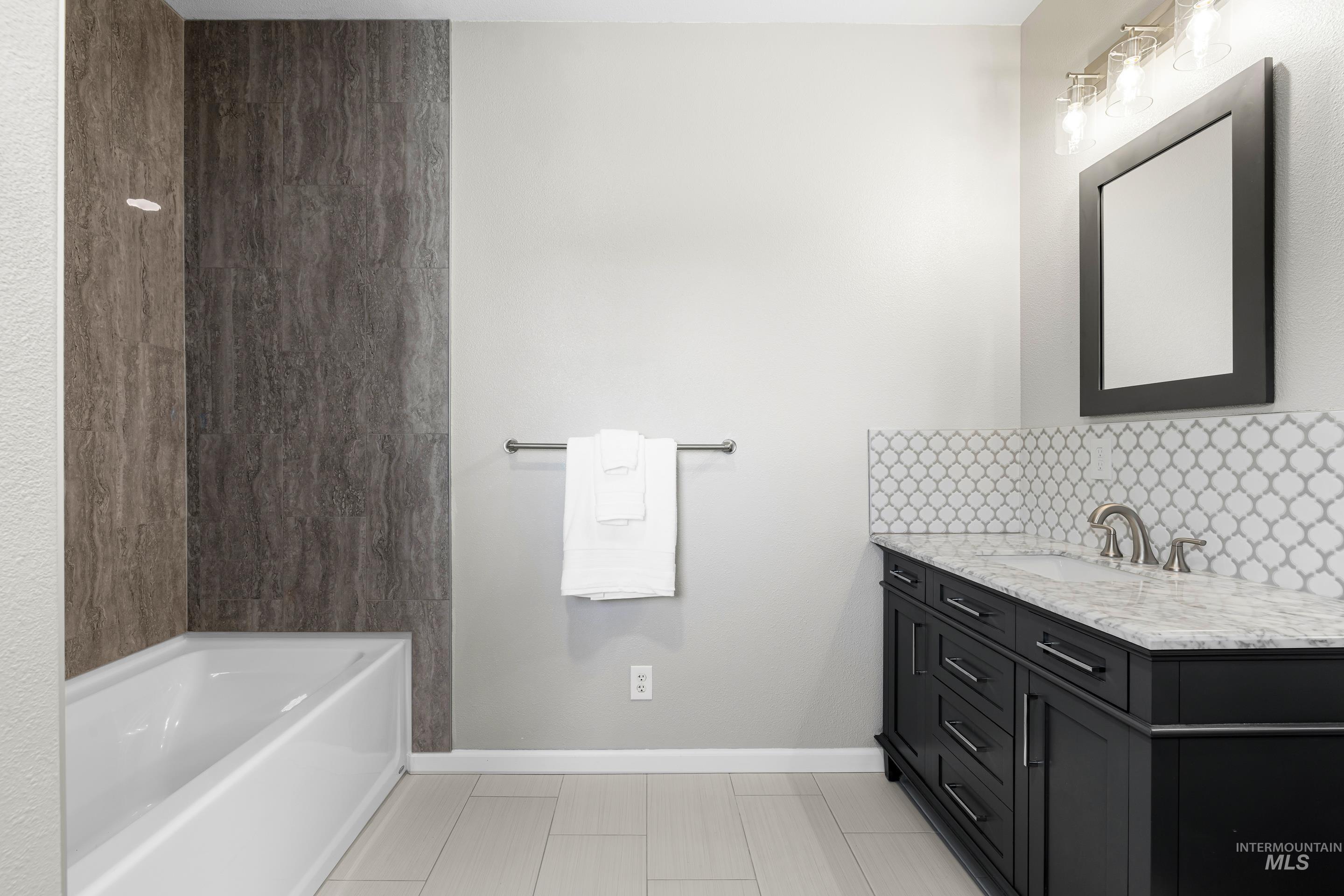 14119 Silver Ridge Road Caldwell, ID 83607 - Photo 38 of 50 Bathroom featuring tasteful backsplash, vanity, a garden tub, and light tile patterned floors