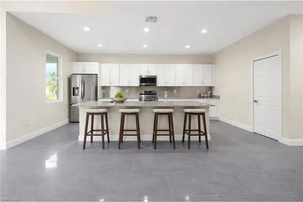 a kitchen with stainless steel appliances granite countertop a table chairs sink and cabinets